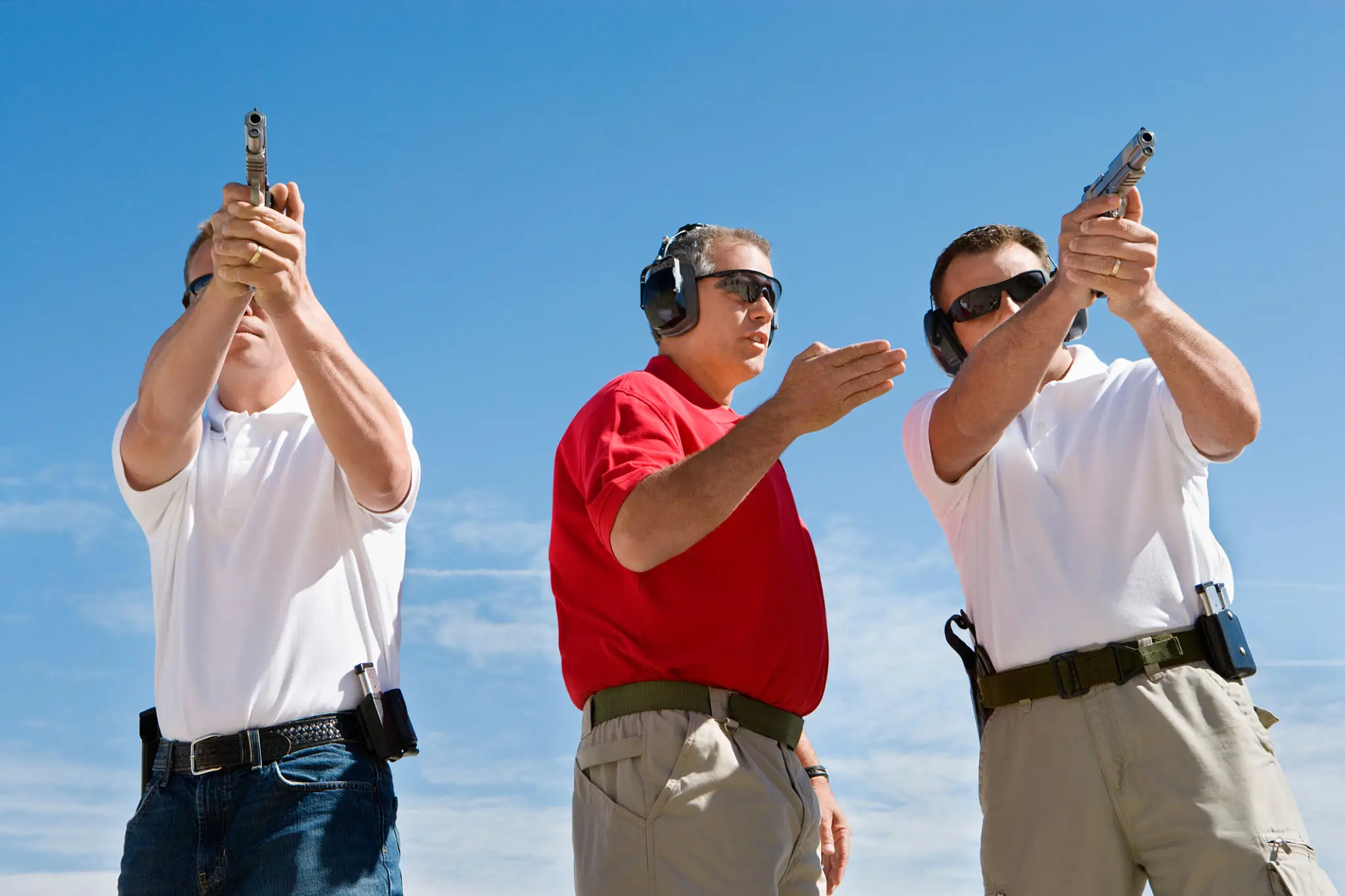 firearm instructor instructing two students at the shooting range