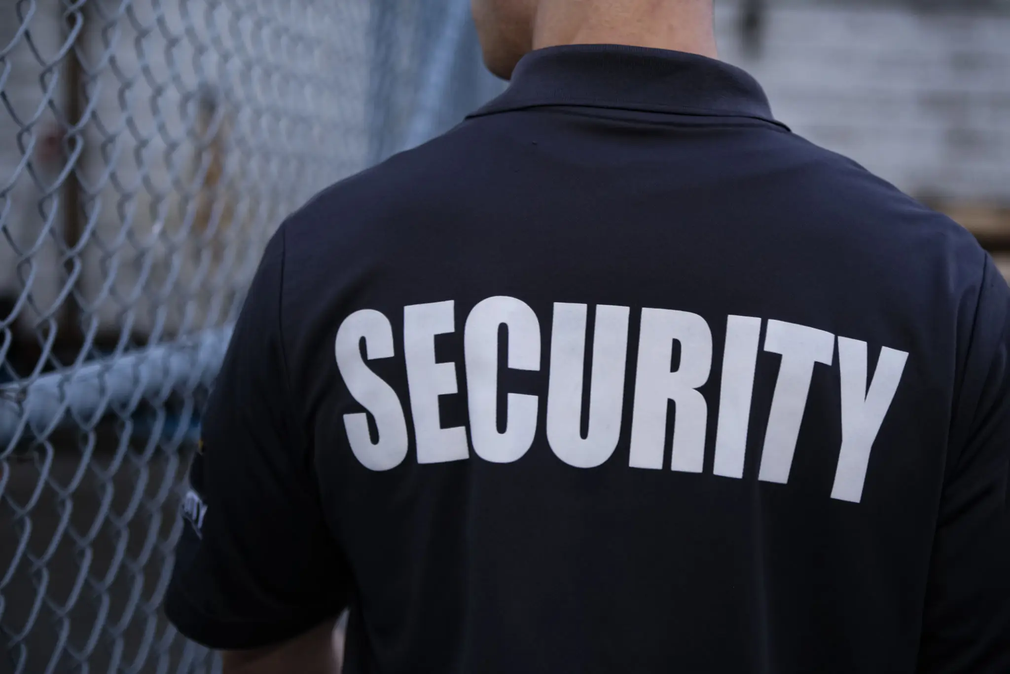 back of a security man's t-shirt in big letters saying "security"